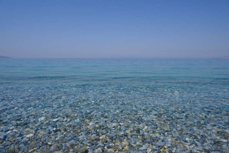 tranquil-pebble-beach-with-clear-blue-waters-under-a-bright--33407317