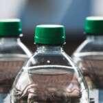 focused-view-of-three-clear-plastic-bottles-with-green-caps--31699476