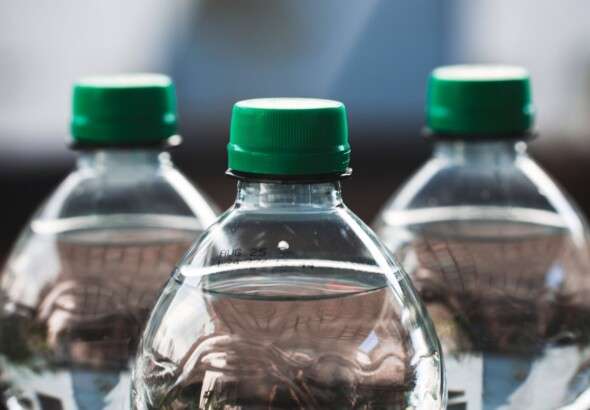 focused-view-of-three-clear-plastic-bottles-with-green-caps--31699476