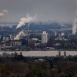 urban-landscape-showing-factories-with-smoke-and-a-bridge-ov-35716659