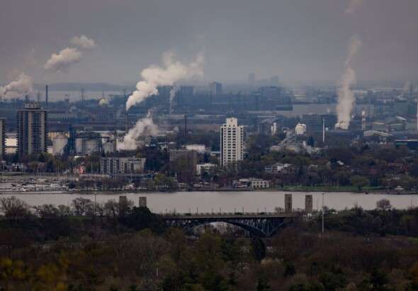 urban-landscape-showing-factories-with-smoke-and-a-bridge-ov-35716659