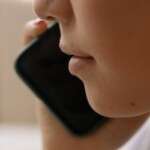 a-close-up-of-someone-talking-on-a-smartphone-focusing-on-th-6964143