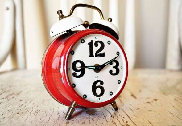 close-up-of-vintage-red-alarm-clock-on-rustic-wood-surface-i-280254