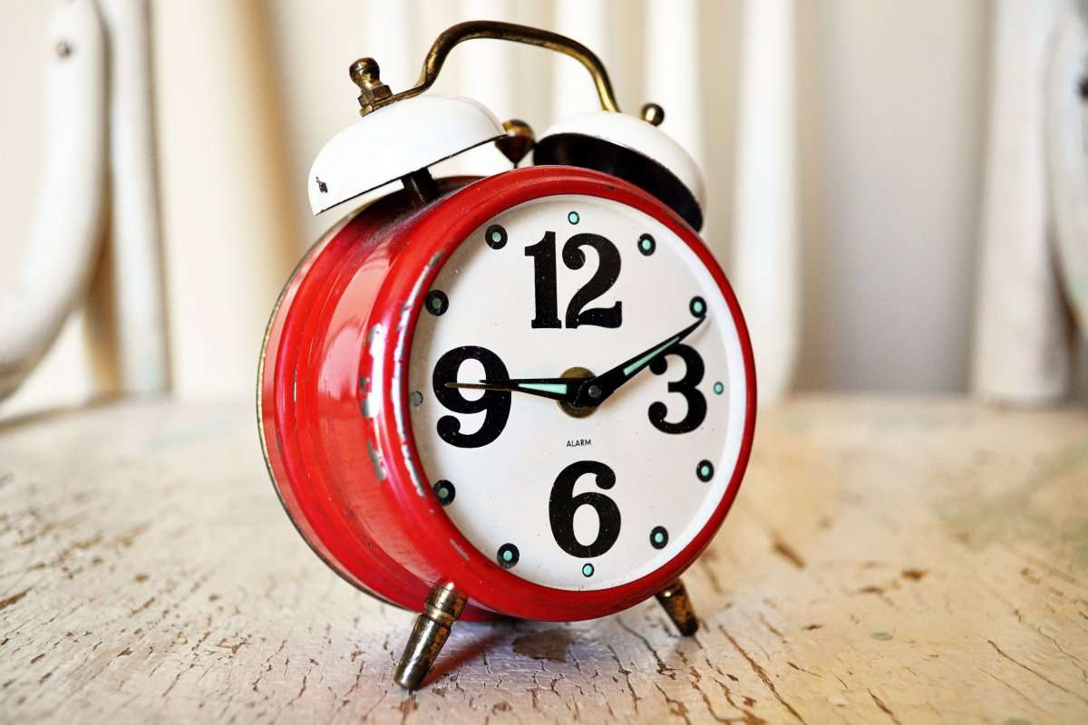 close-up-of-vintage-red-alarm-clock-on-rustic-wood-surface-i-280254
